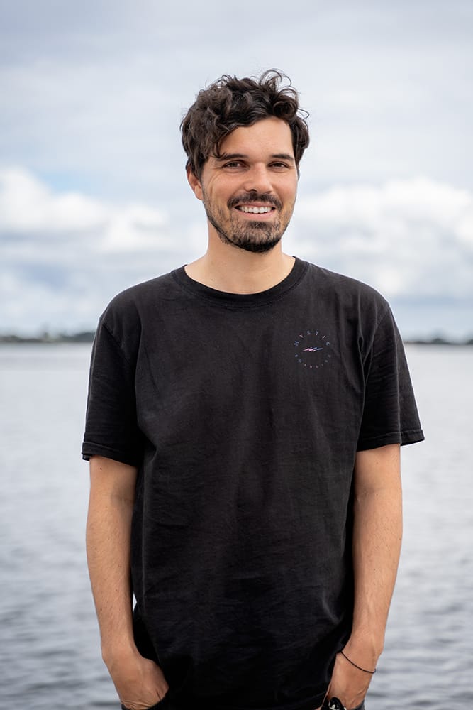 Dario, smiling, standing in front of the sea.