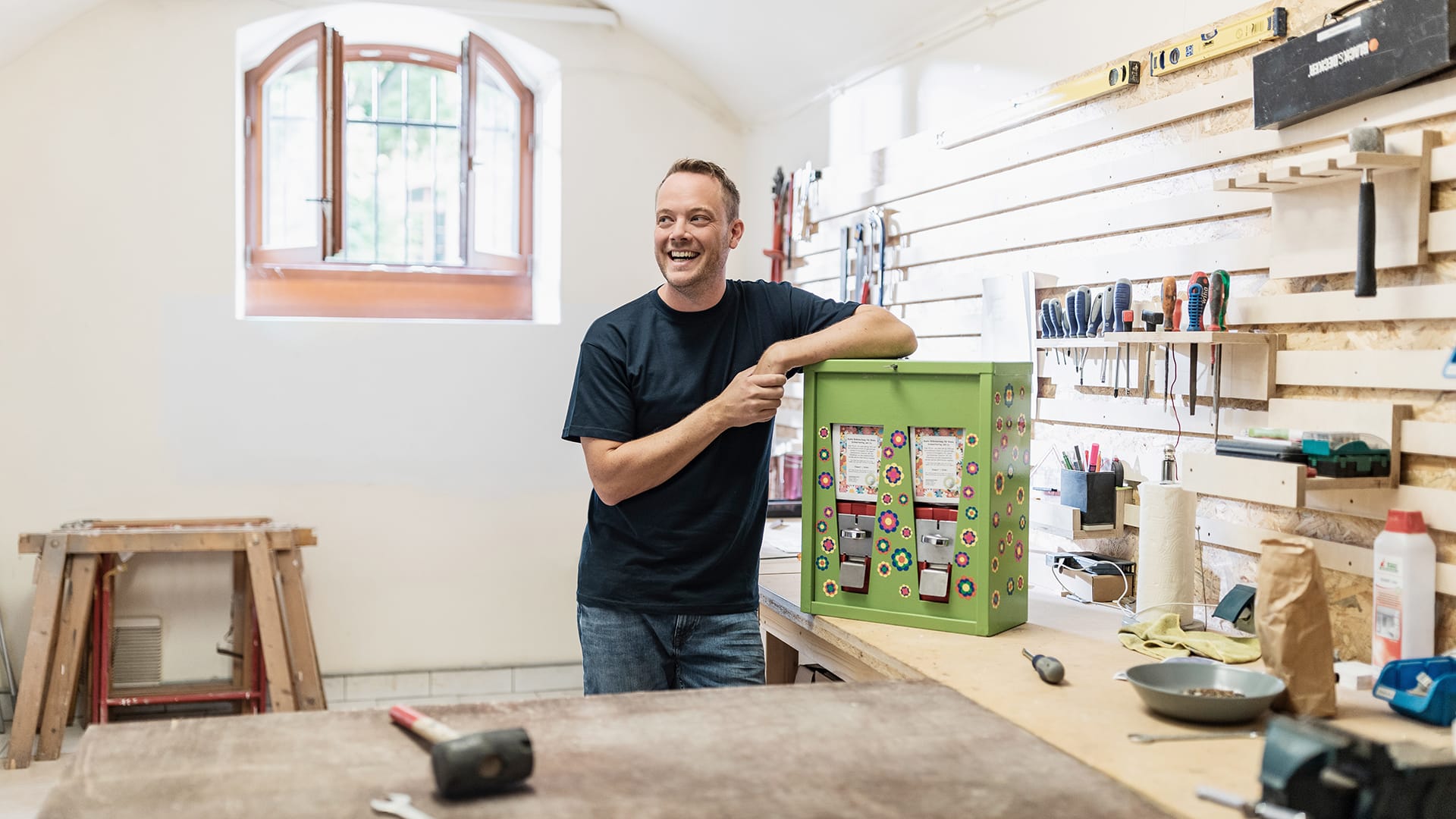 Smiling man standing inside his workshop